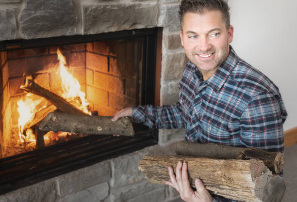 Nice man with logs in the hands, His putting wood in the fireplace at home